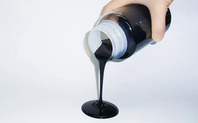 A person pouring black liquid from a bottle.